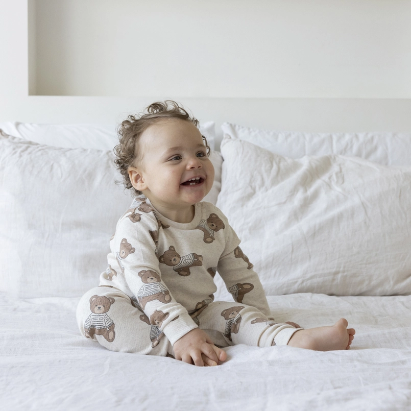 Baby op bed in Feetje Teddy Bear-pyjama, originele modelfoto bij Kixx