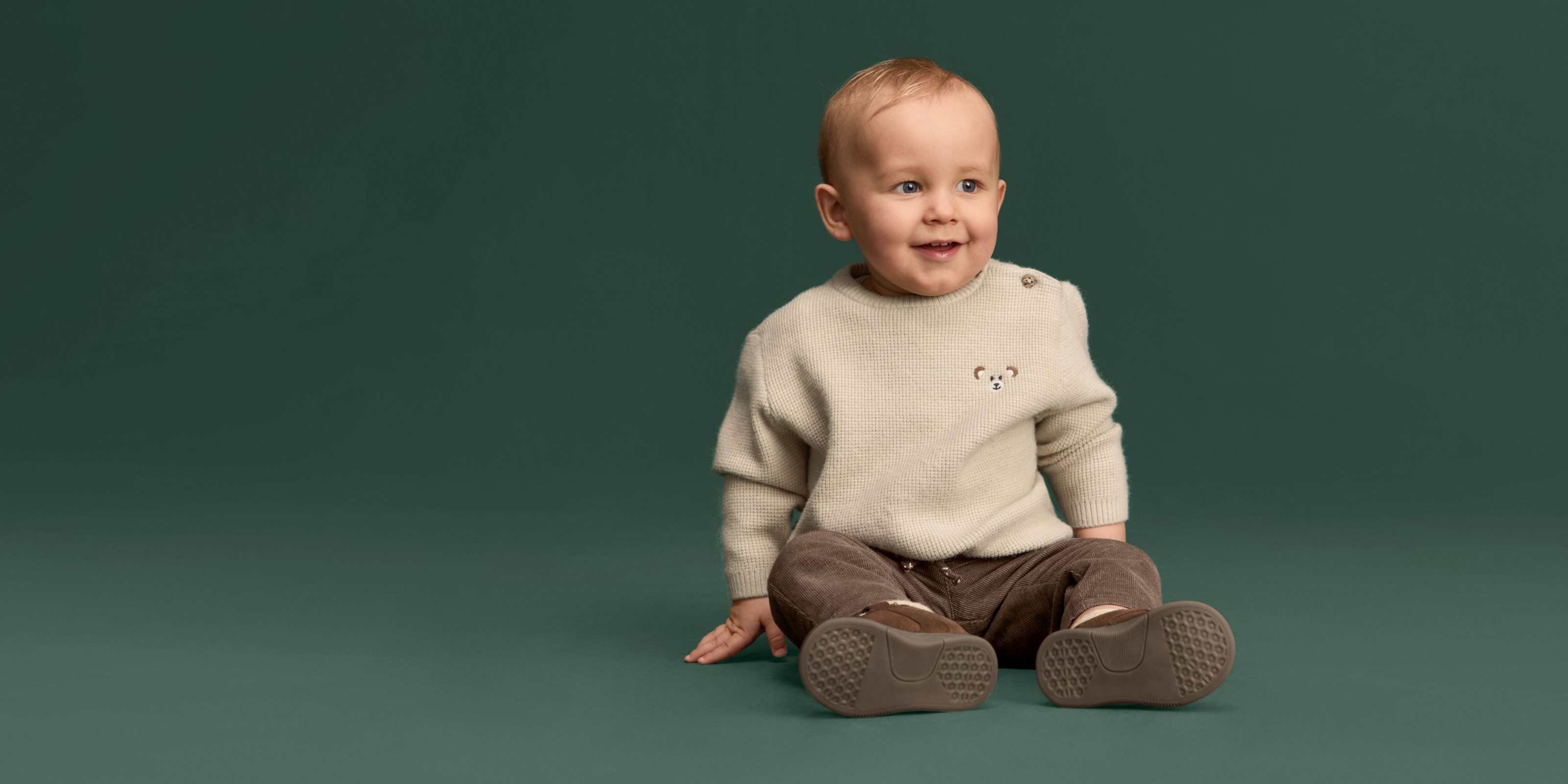 Baby in een crème gebreide trui bij C&A