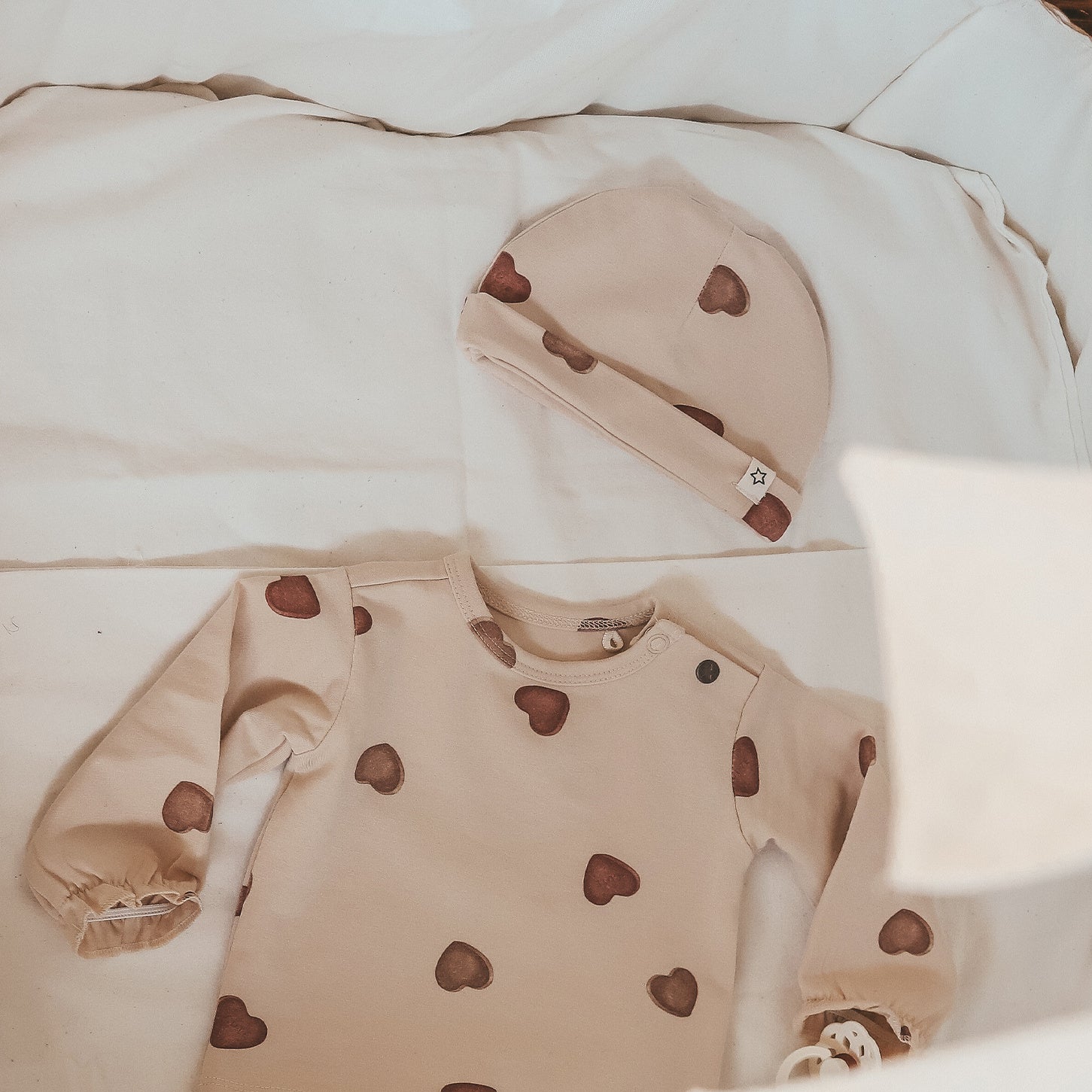 Officiële Your Wishes-sfeerfoto met compleet babymutsje op beddengoed.