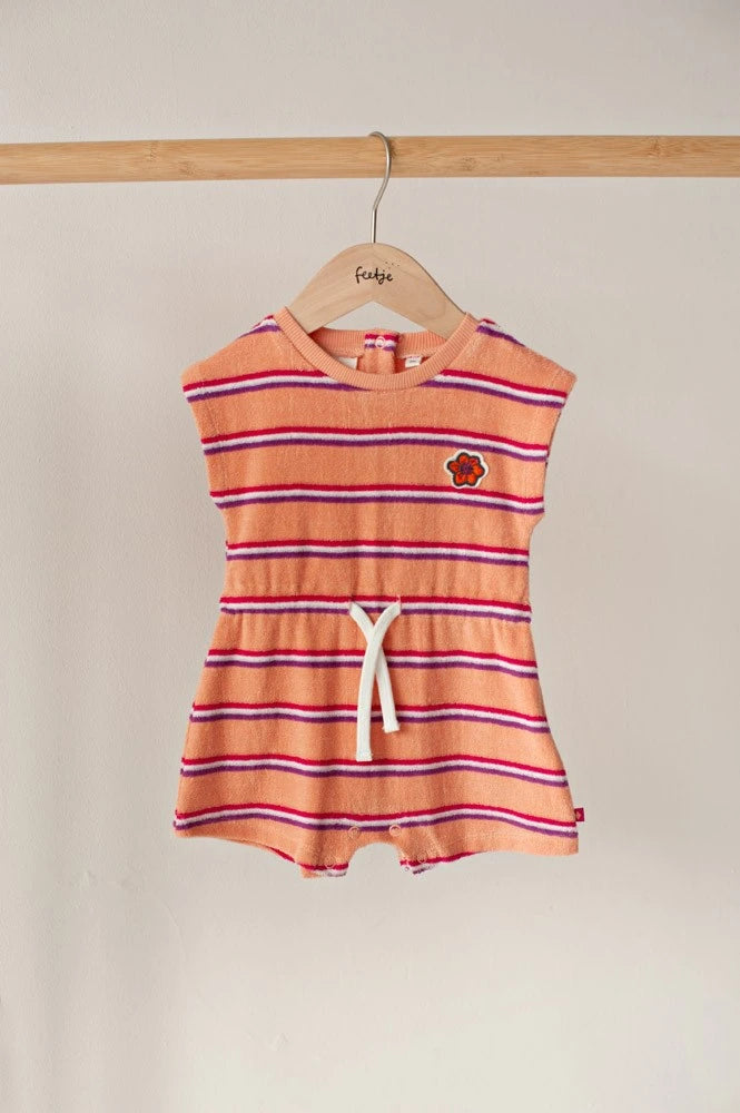 Een volledige kleurrijke babyplaysuit aan een kledinghanger op de oorspronkelijke warme achtergrond.