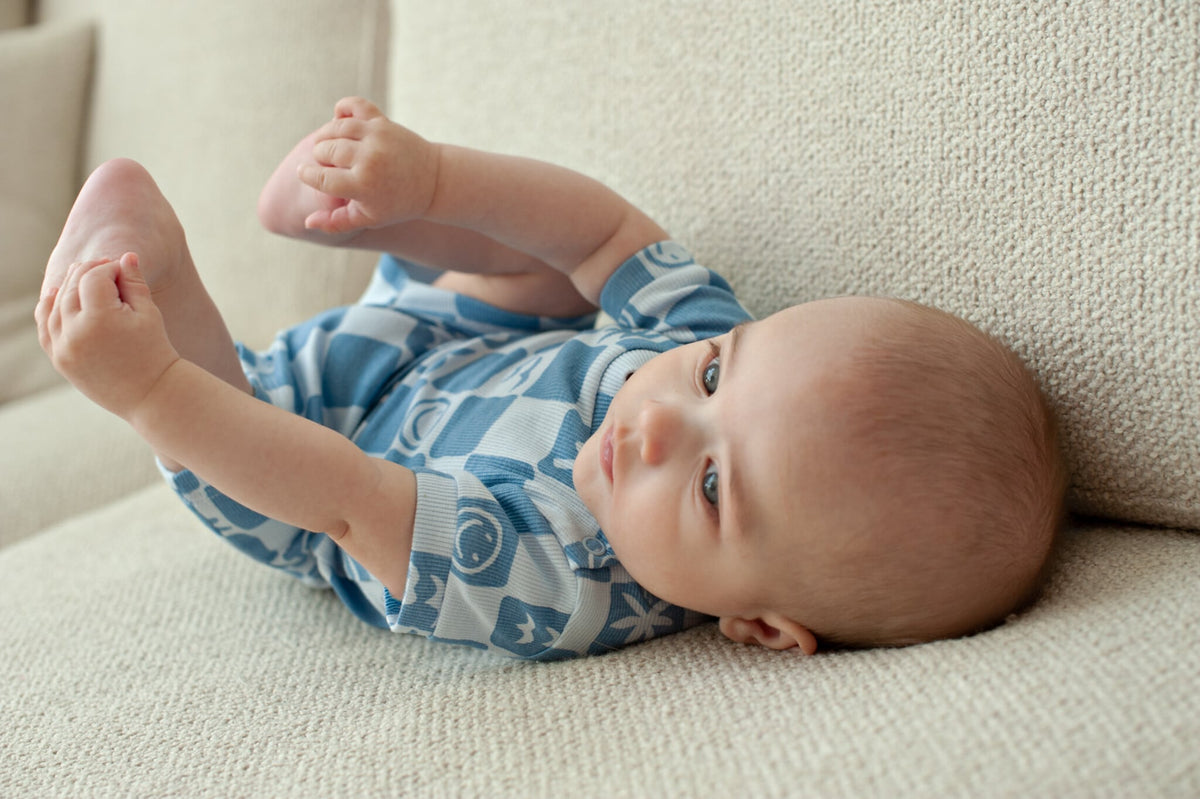Baby in een blauwe Feetje-pyjama op een bank.