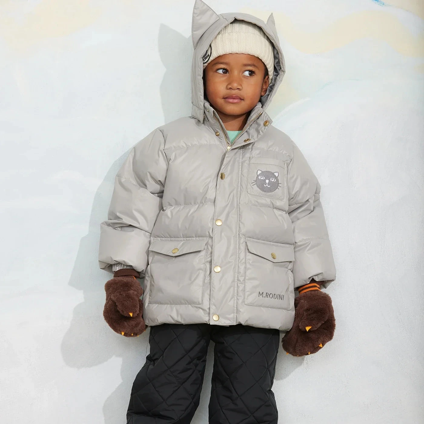 Kind in een Mini Rodini-winterjas met kattenoren aan de capuchon