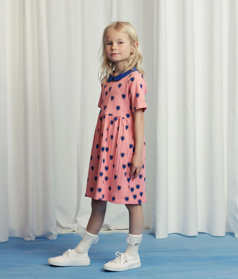Kind in een roze Mini Rodini-jurk met blauwe hartjes