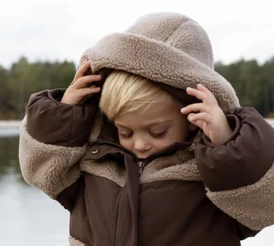 Kind in een bruine Donsje-winterjas met muts