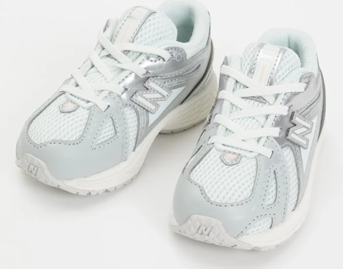 Een paar lichtgekleurde New Balance-kindersneakers met mesh