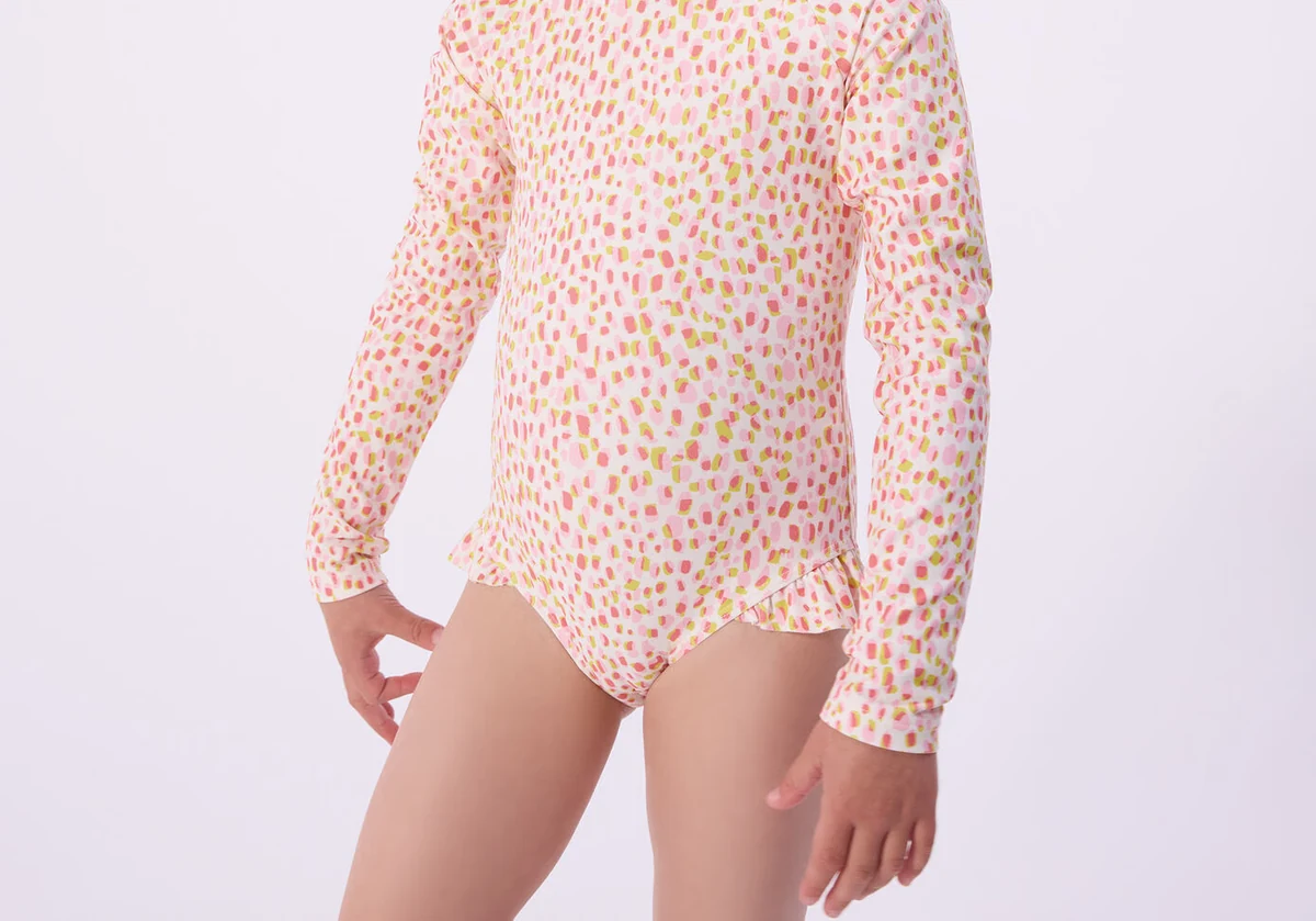 Gedragen detail van een Petit Bateau-zwembody met gekleurde print en lange mouwen