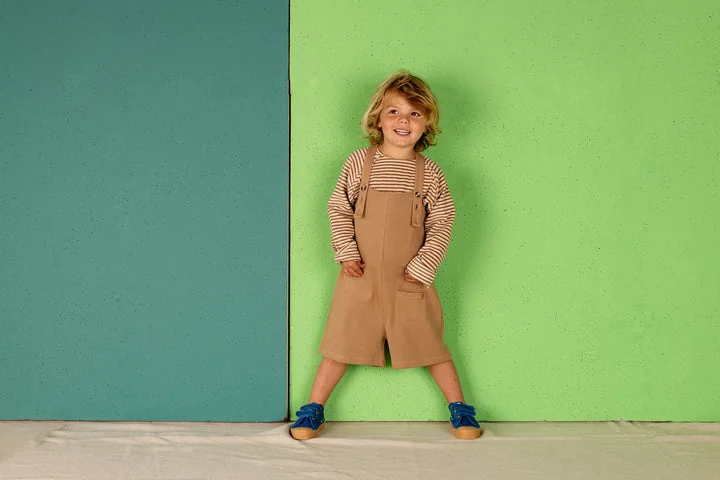 Kind met een beige Nixnut-playsuit