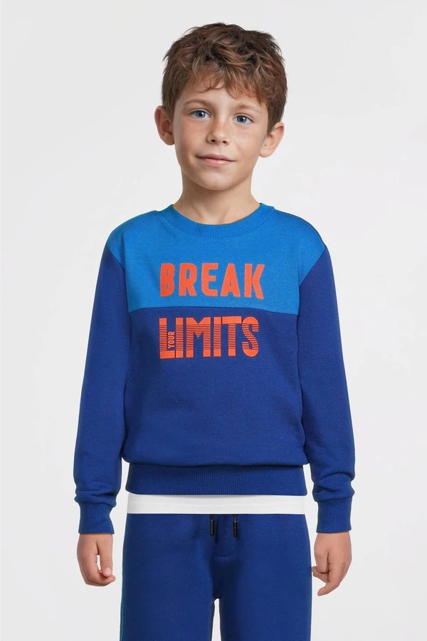 Jongen in een felblauwe colourblock-sweater met oranje tekst uit het officiële Wehkamp-aanbod