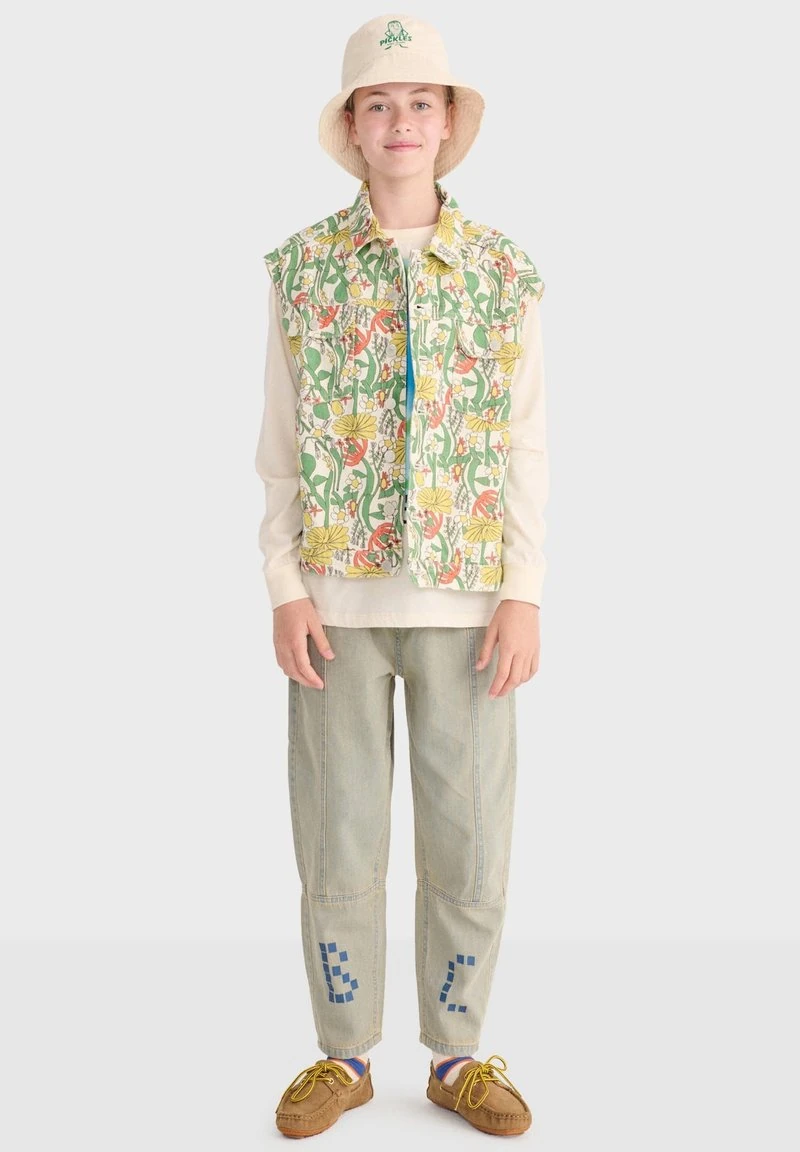 Kind draagt een vest met bloemenprint, een crèmekleurig shirt met lange mouwen, licht denim broek met blauwe patches, een beige emmerhoed en bruine mocassins.